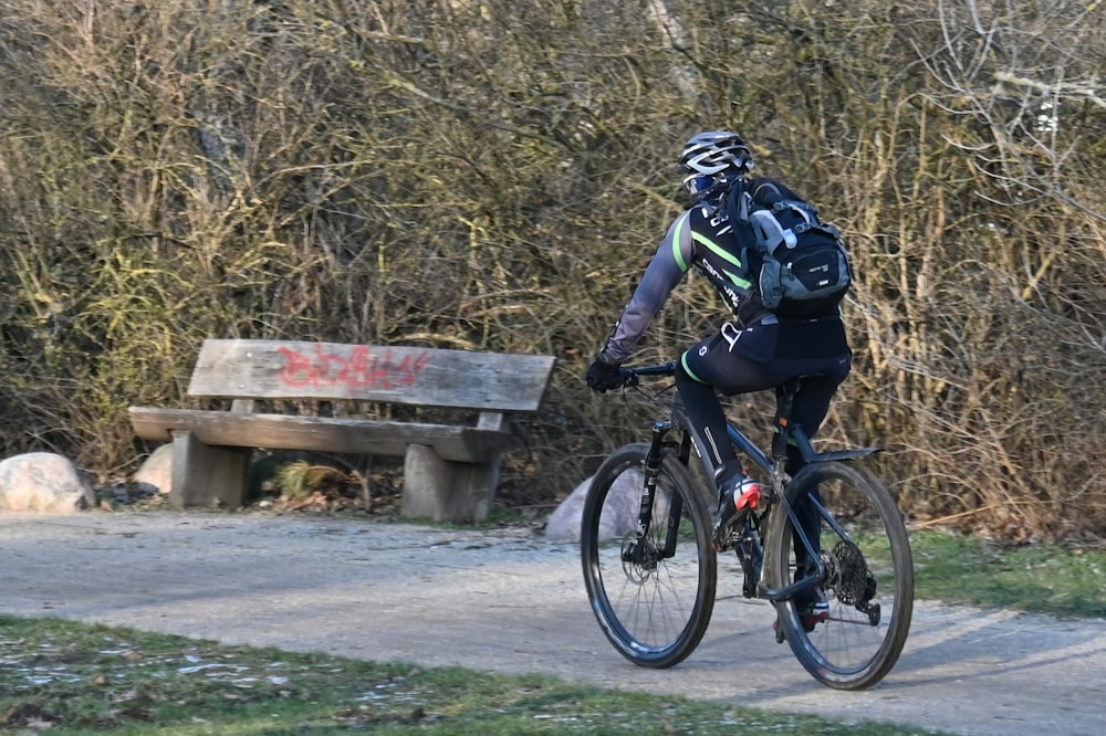 a man riding a bike down a path next to a bench