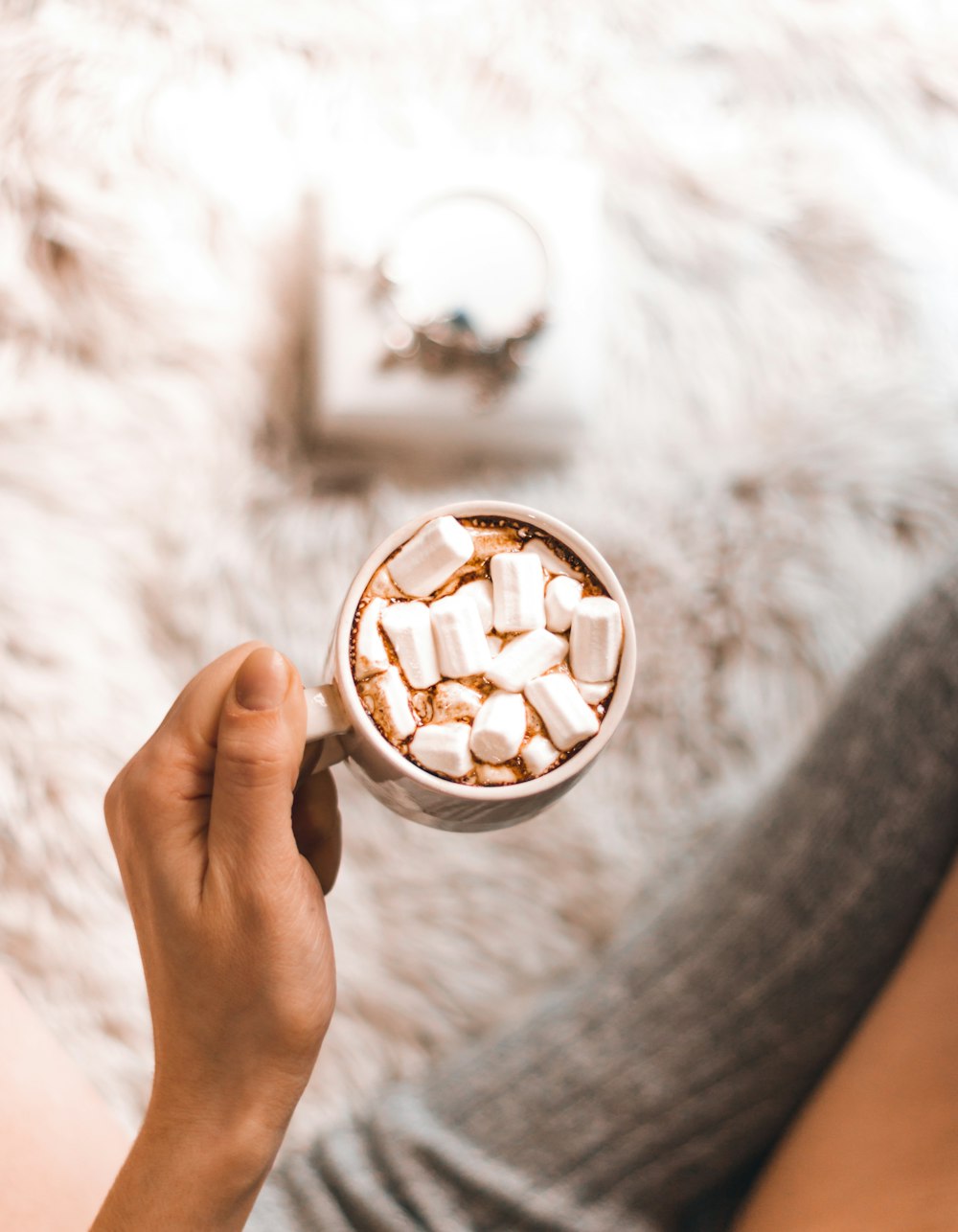a person holding a cup of hot chocolate with marshmallows