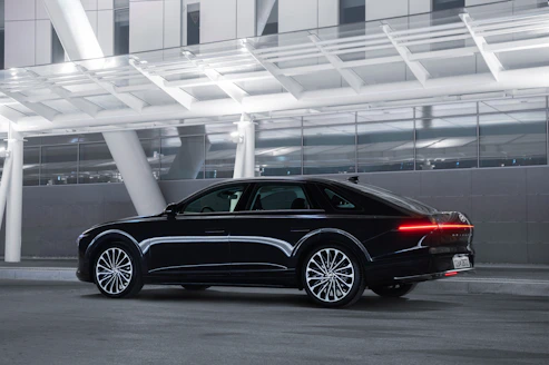 A sleek executive car waiting outside a modern airport terminal.