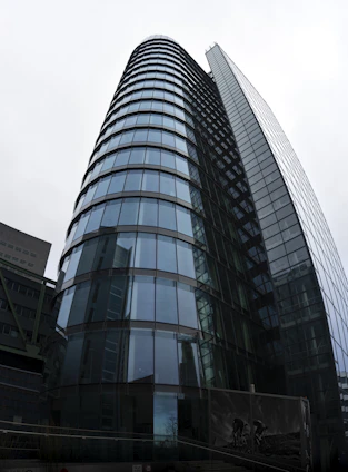 Modern glass facade of a premium residential building showcasing sleek enclosures and elegant reflections.
