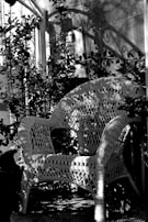 A cozy rattan outdoor lounge chair nestled beside blooming garden plants.