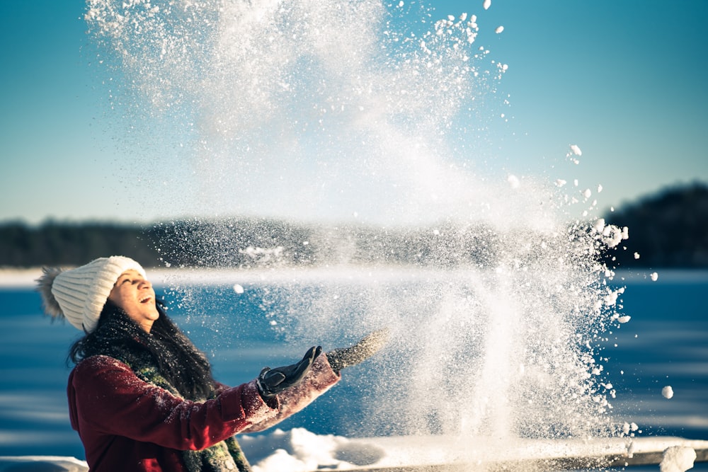 a woman in a red jacket throwing snow into the air