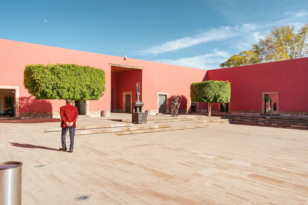 a man standing in front of a pink building