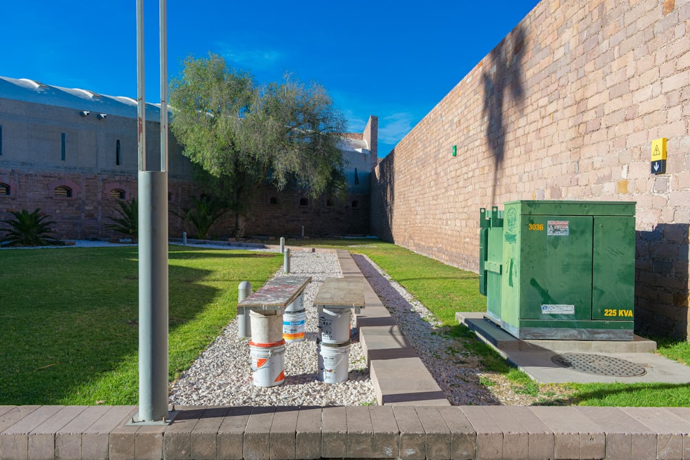 a brick building with a green trash can next to it