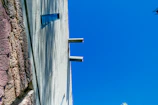 Close-up of textured concrete walls contrasting with smooth glass surfaces under a clear sky.