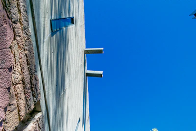 Close-up of textured concrete walls contrasting with smooth glass surfaces under a clear sky.