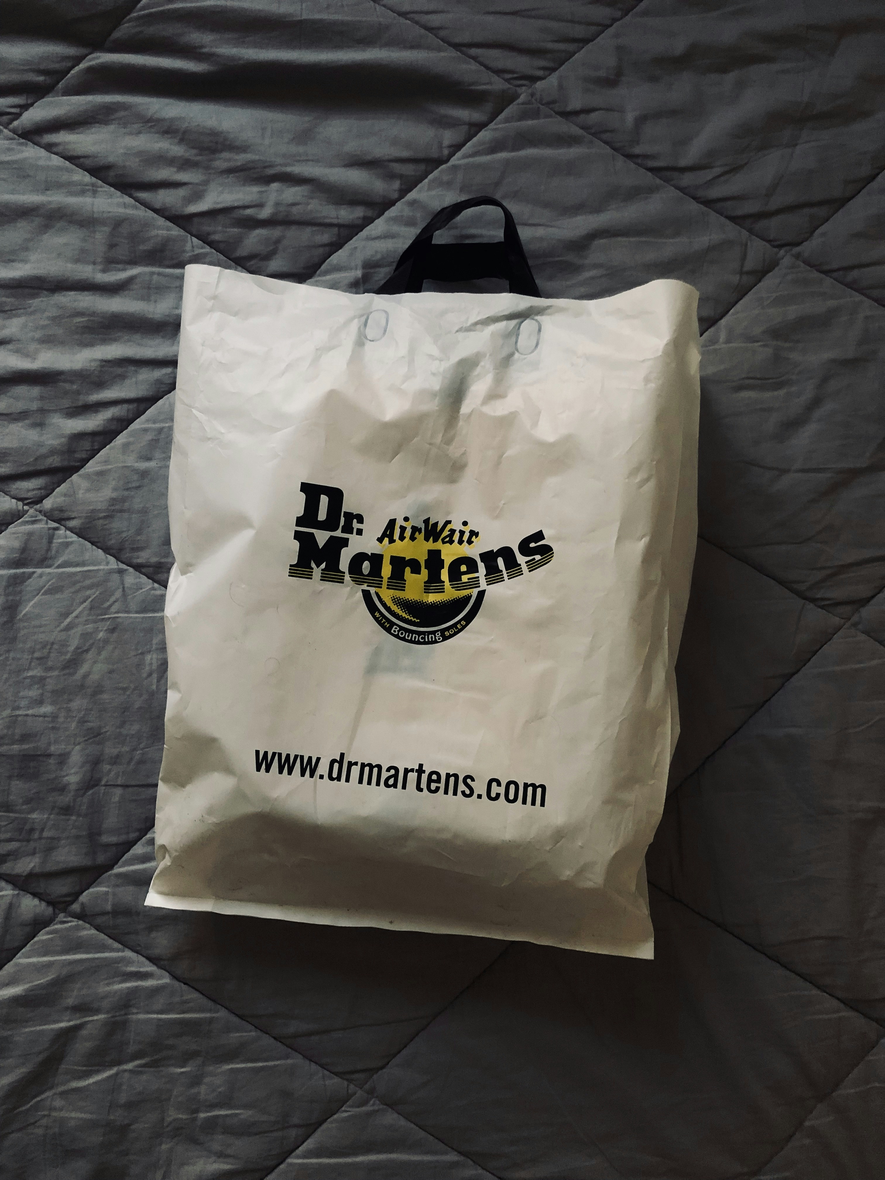 a white bag sitting on top of a bed