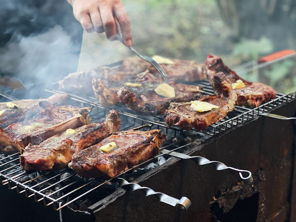 a person is cooking steaks on a grill