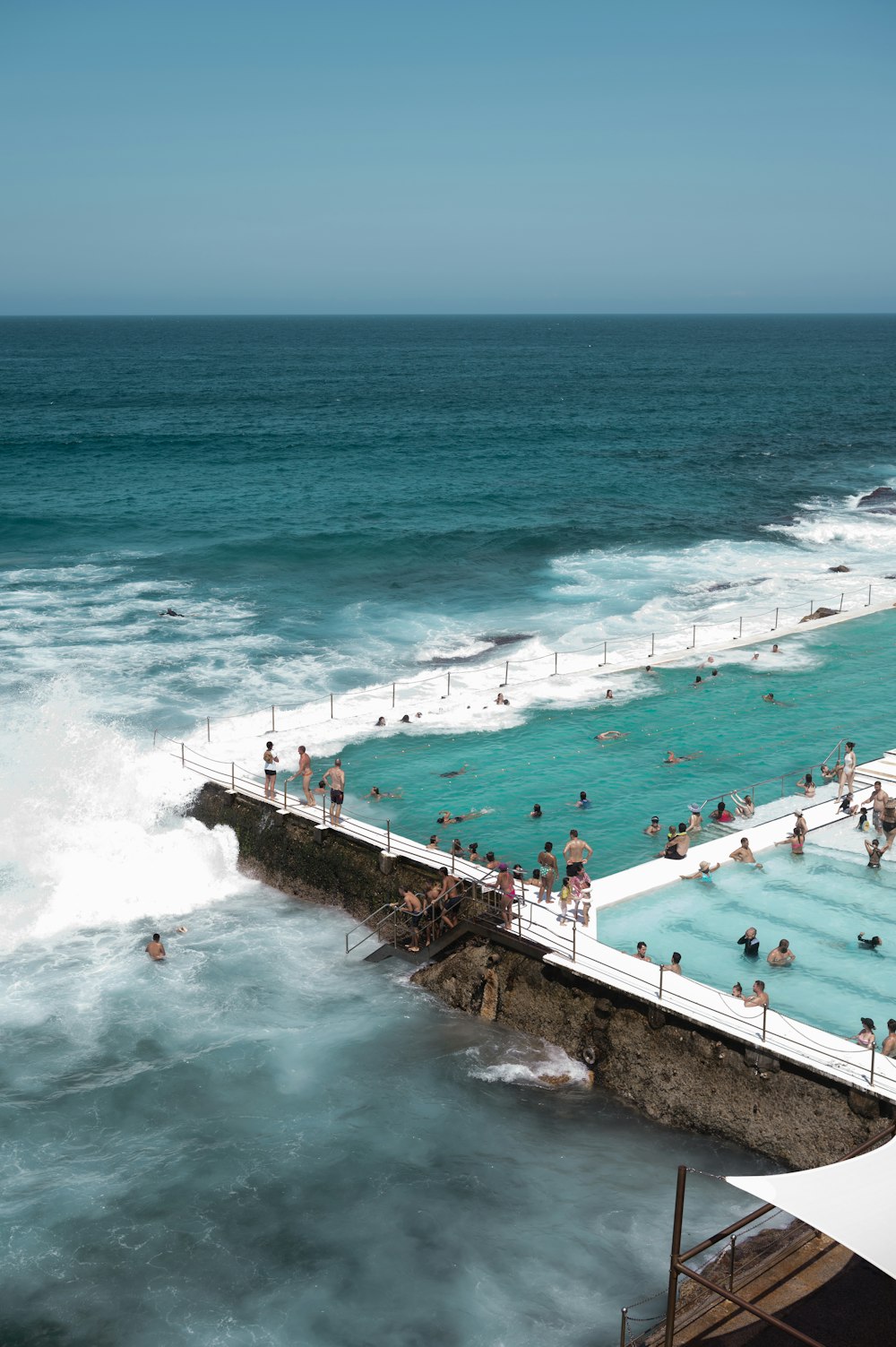 a group of people swimming in a pool next to the ocean