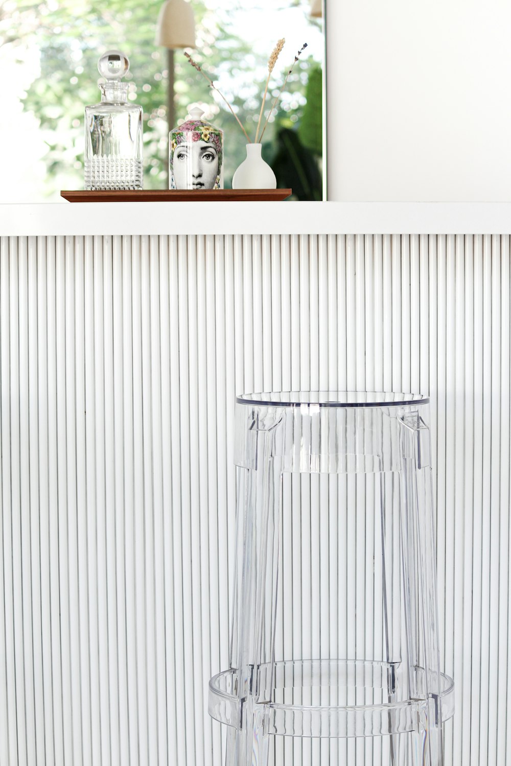 a clear stool sitting in front of a white wall