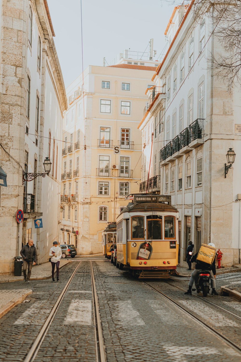 a yellow trolley car traveling down a street next to tall buildings