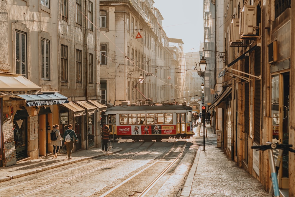 a red trolley car traveling down a street next to tall buildings