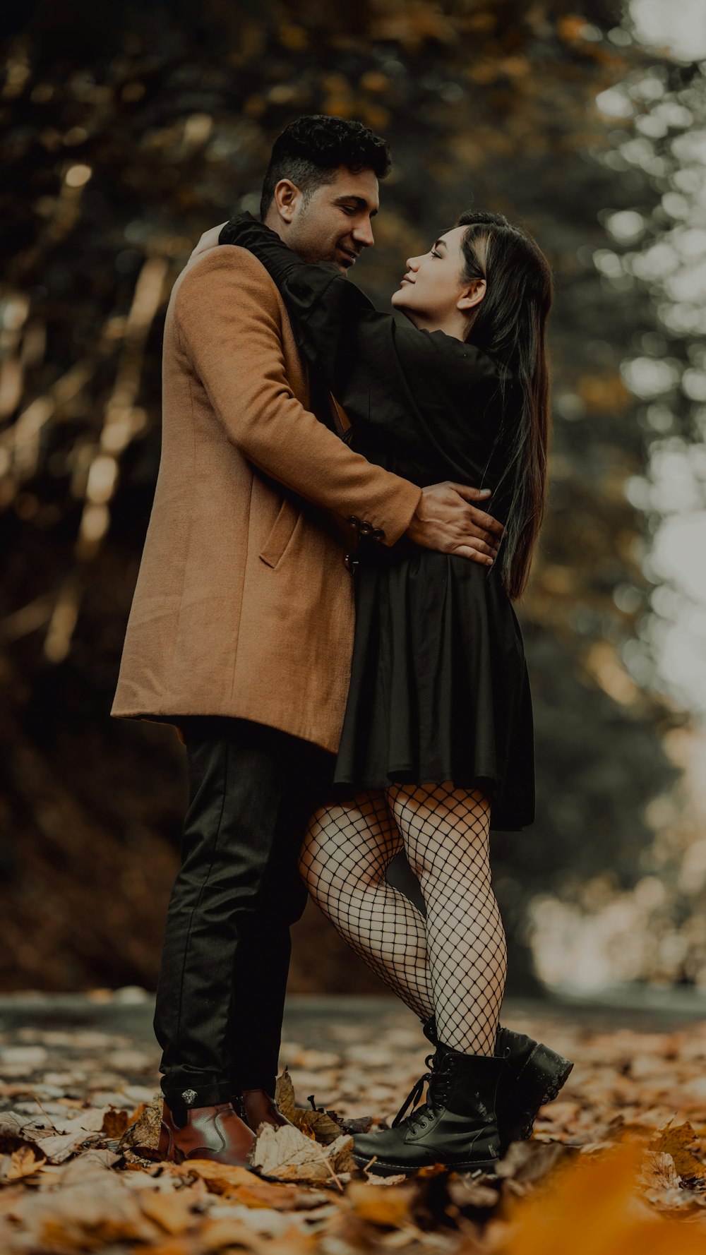 a man and a woman are hugging in the leaves