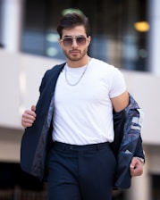 Portrait of a confident man in his 30s wearing a stylish chain necklace against a soft white background.