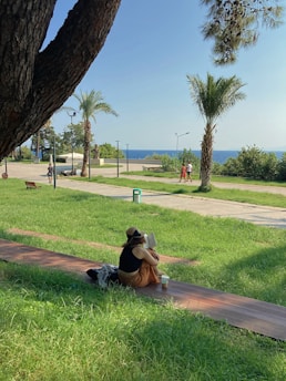 Person smiling while listening to an audiobook on a city park bench.
