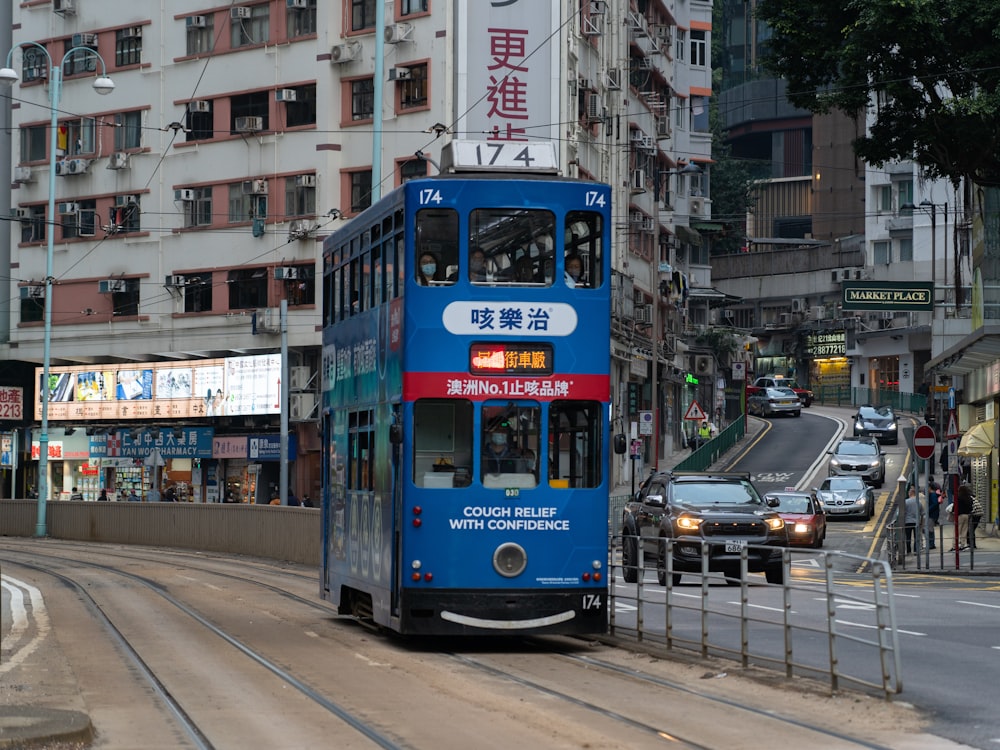 a blue double decker bus driving down a street