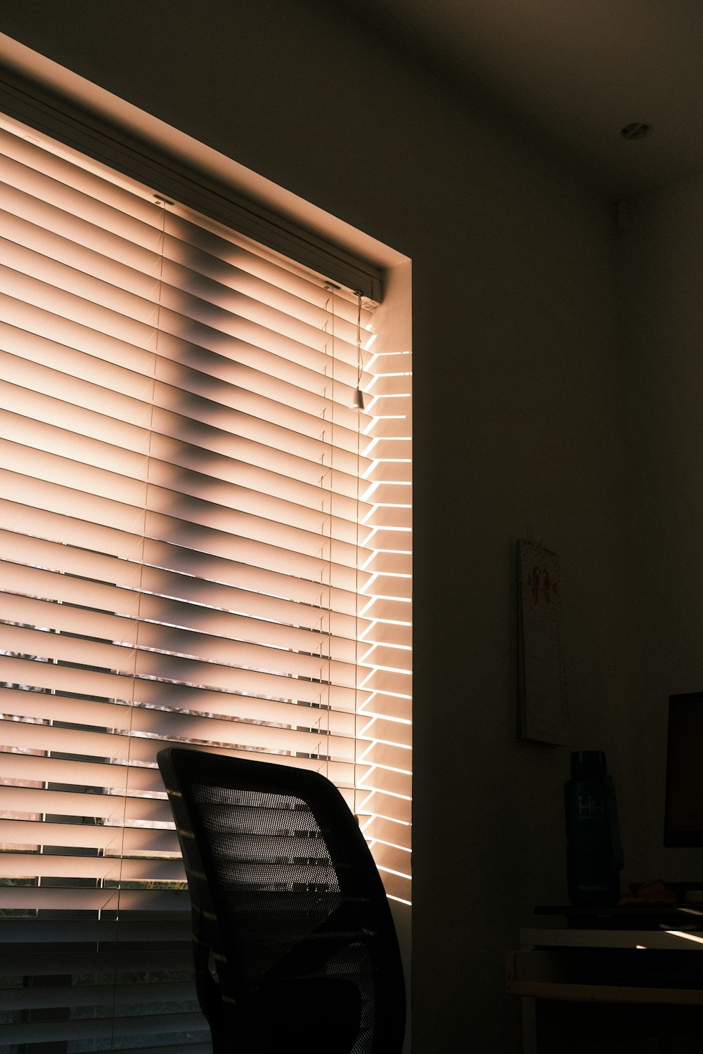 ein Stuhl, der vor einem Fenster sitzt, das mit Jalousien bedeckt ist