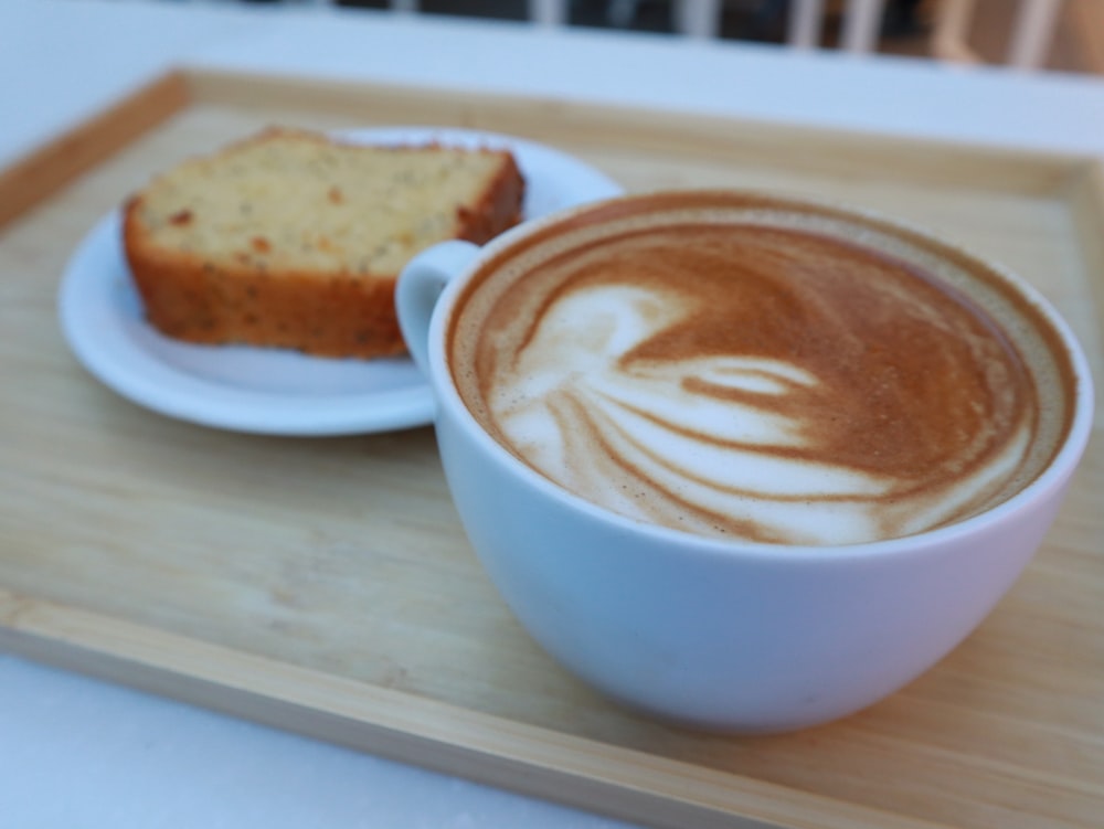 a cup of coffee and a piece of bread on a tray