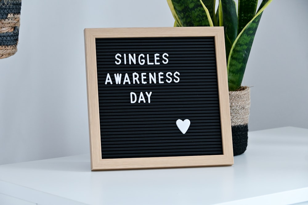 a sign that says singles awareness day next to a potted plant
