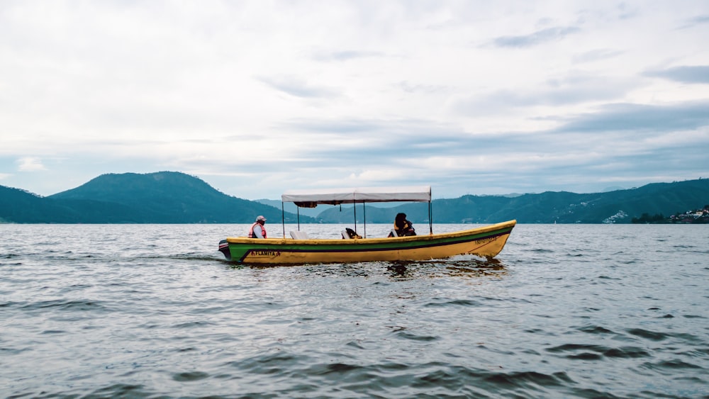 a yellow boat with two people on it in the water