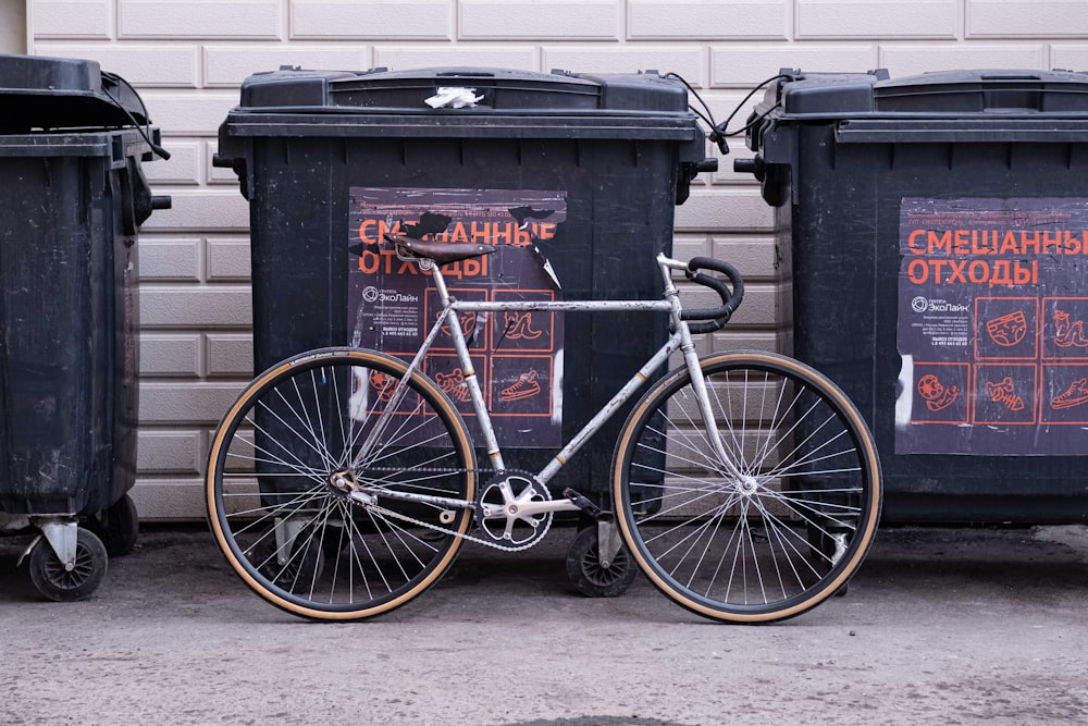 a bicycle parked next to two trash bins