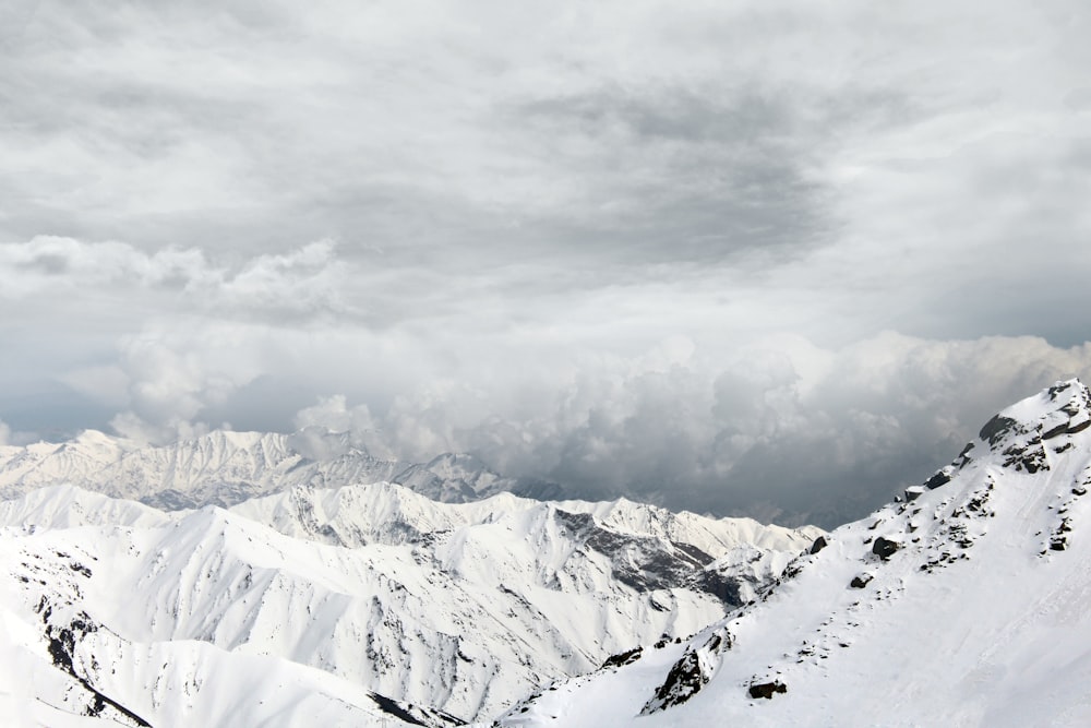 a snow covered mountain range under a cloudy sky