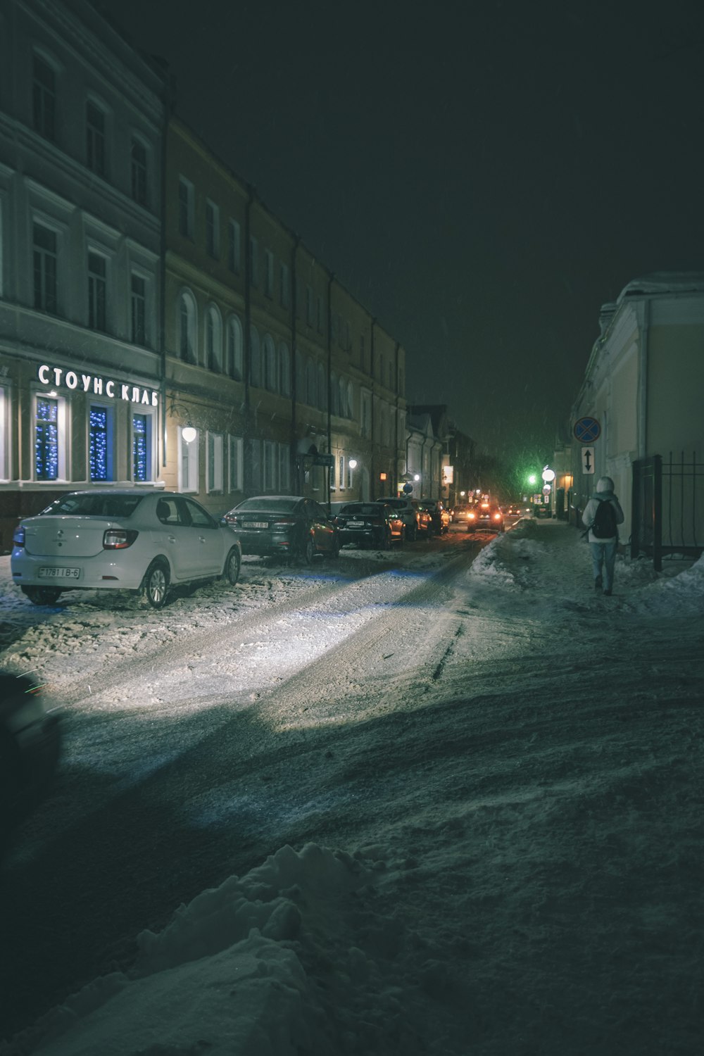 a person walking down a snowy street at night