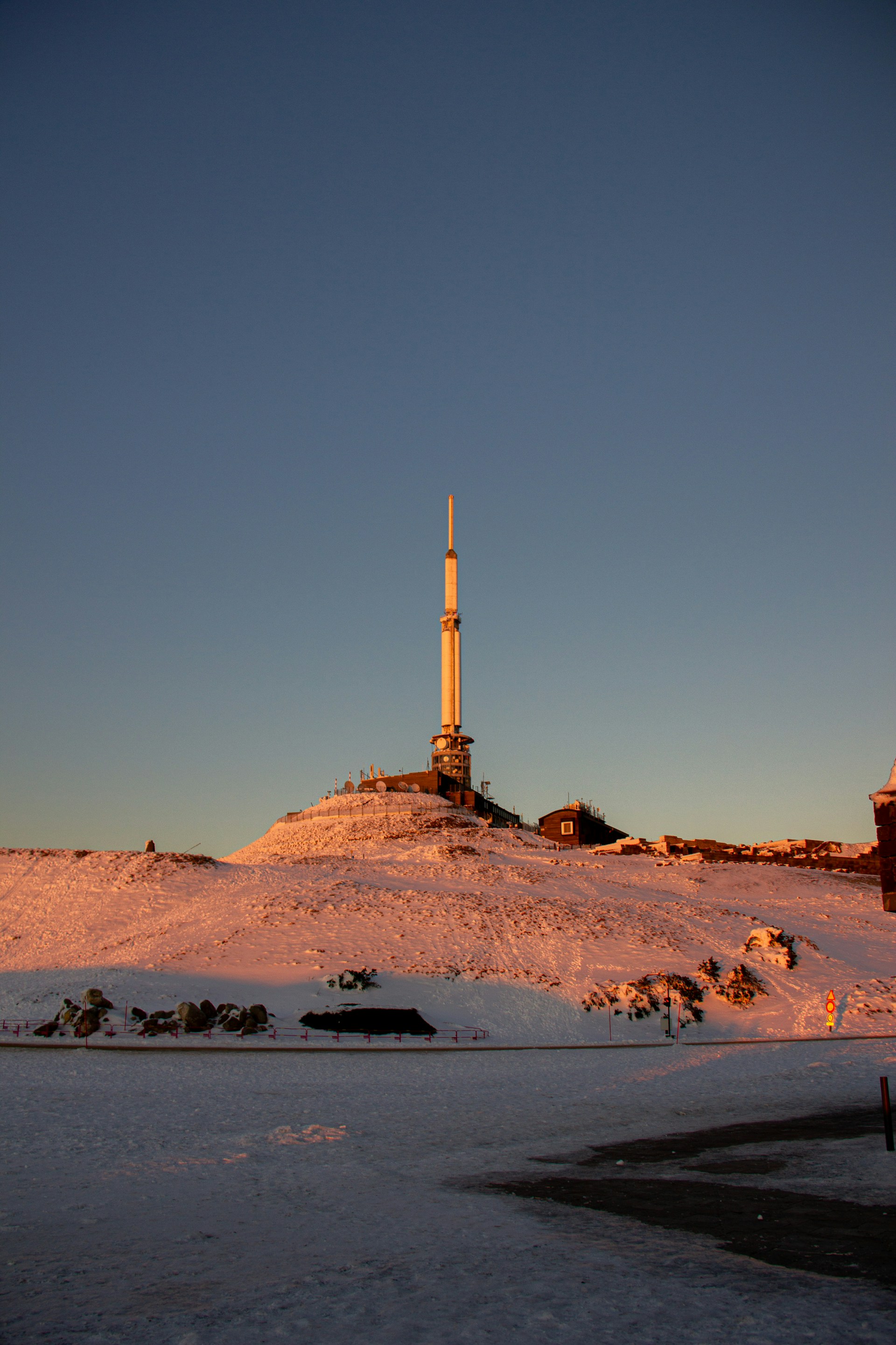 a very tall tower sitting on top of a snow covered hill