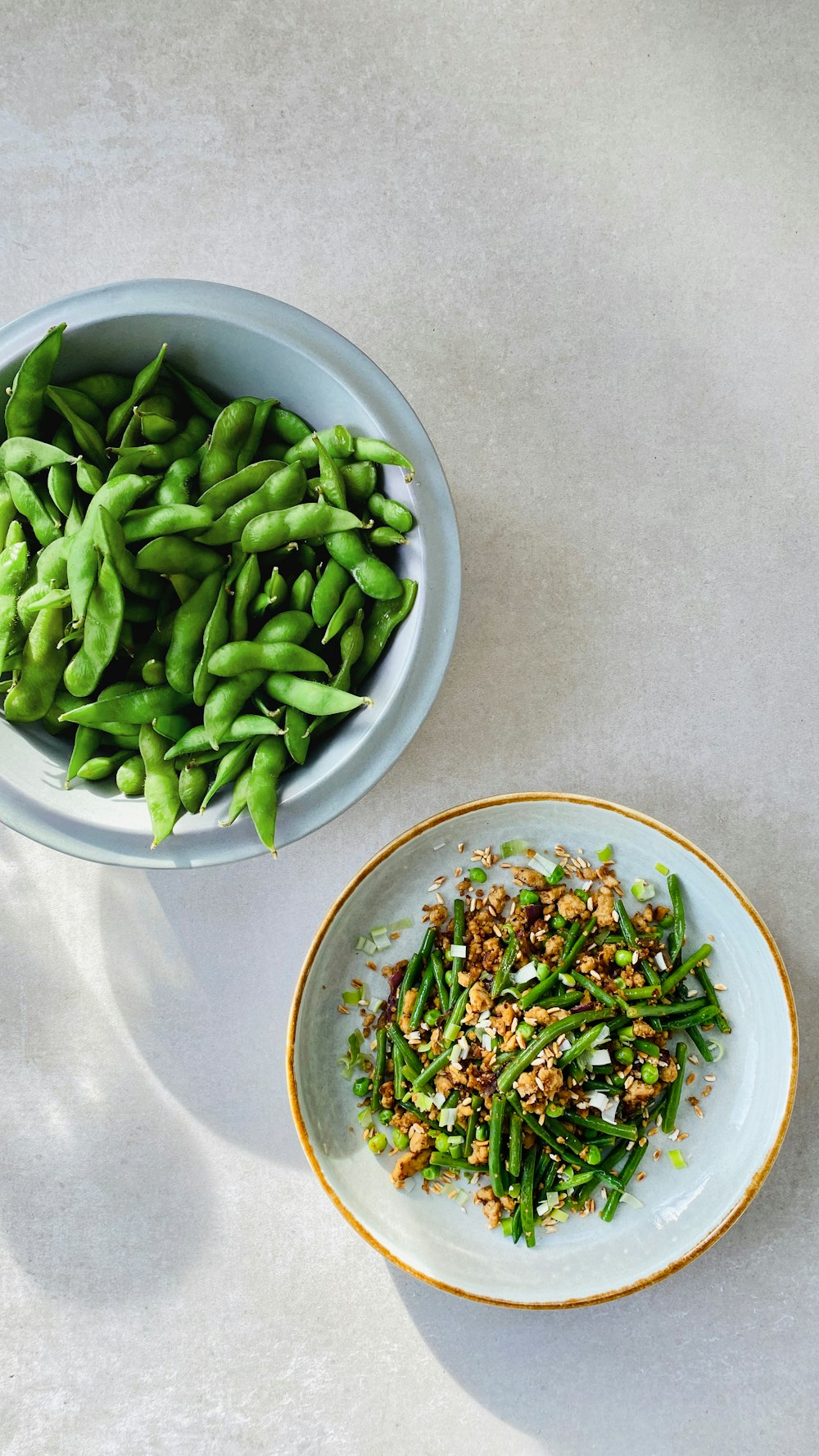 a bowl of green beans next to a bowl of green beans