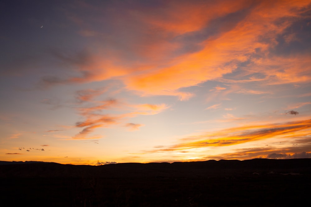 the sun is setting in the sky over a field