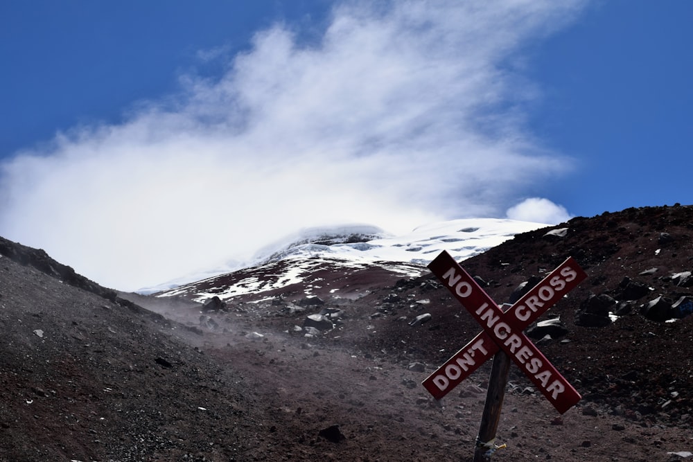 a red and white sign sitting on the side of a mountain