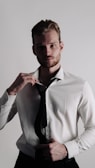 A well-dressed man adjusting his tie in a modern setting.