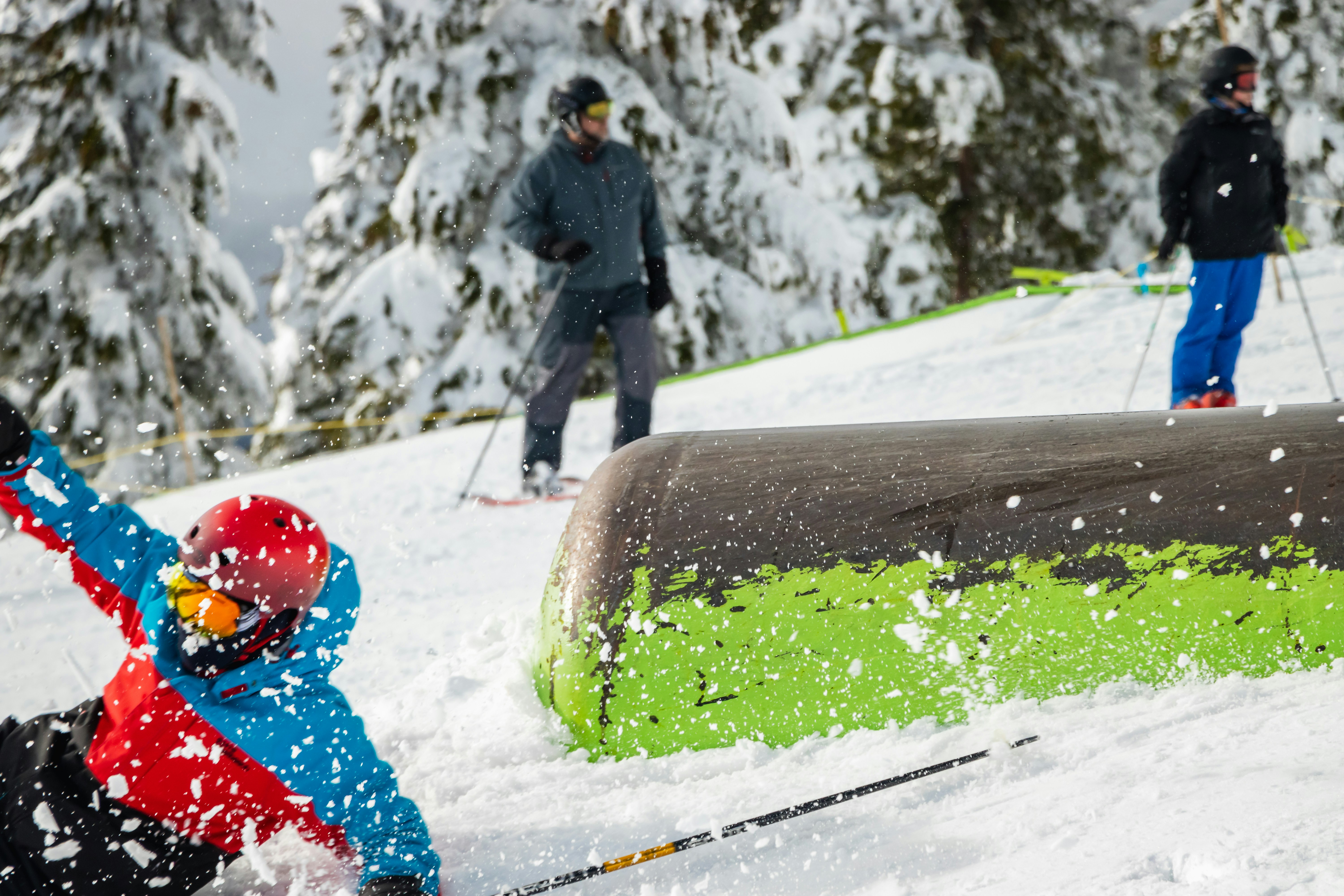 a young child riding skis down a snow covered slope, skier falling while sliding on a steel pipe in a terrain park at Mount Washington, BC