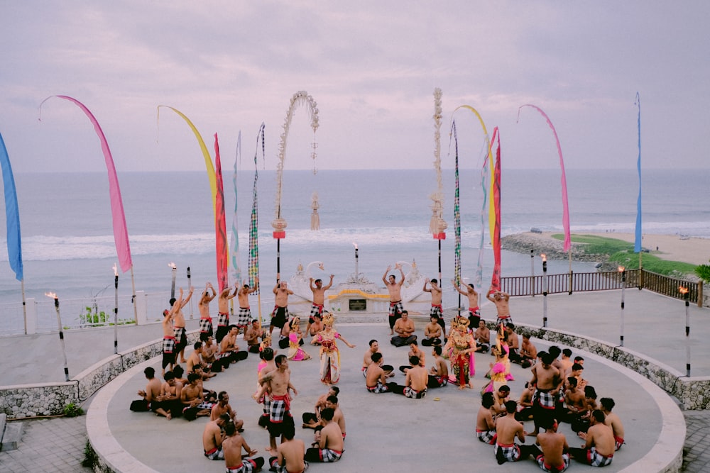 a group of people sitting around each other in front of a body of water