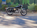 A shiny classic Royal Enfield motorcycle parked against a rustic brick wall.