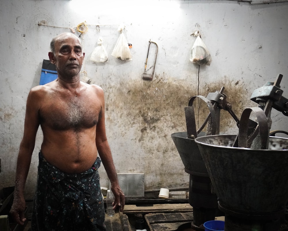 a shirtless man standing in a dirty kitchen