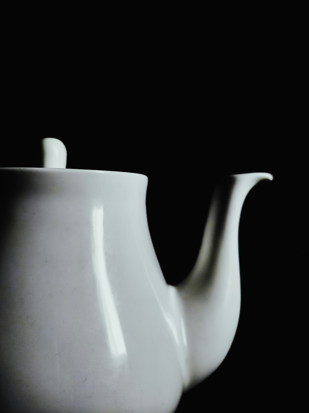 a white tea pot with a black background