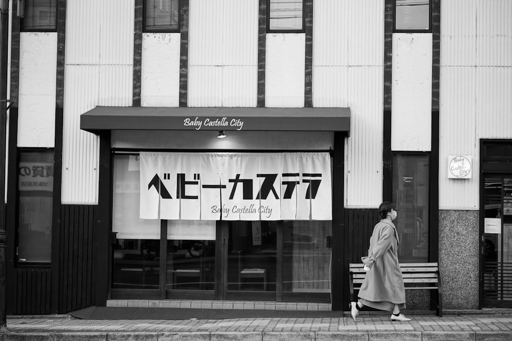 a woman walking down a street past a tall building