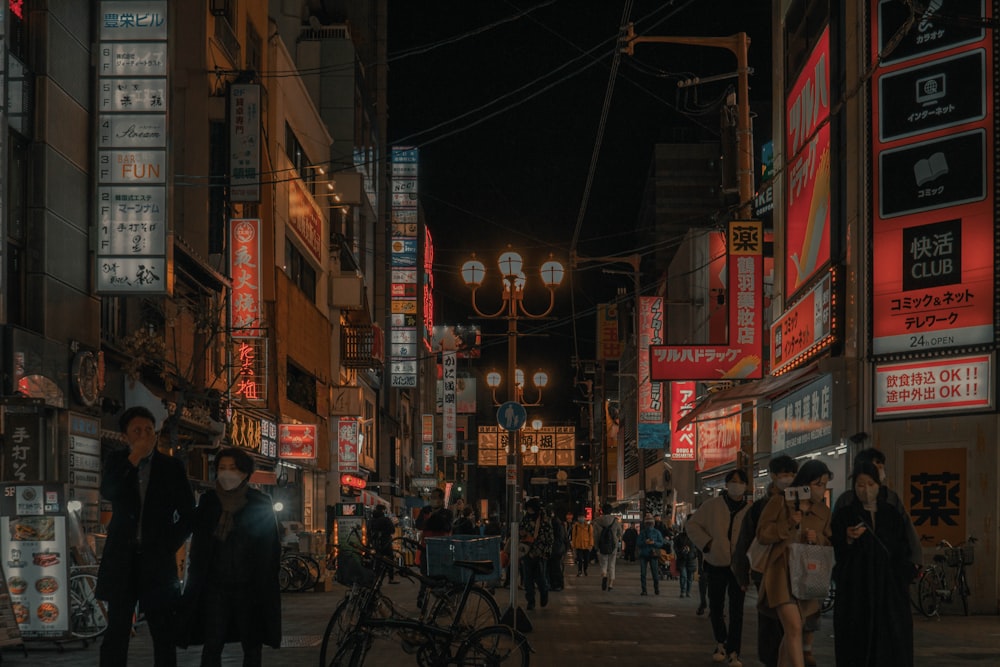 a group of people walking down a street at night