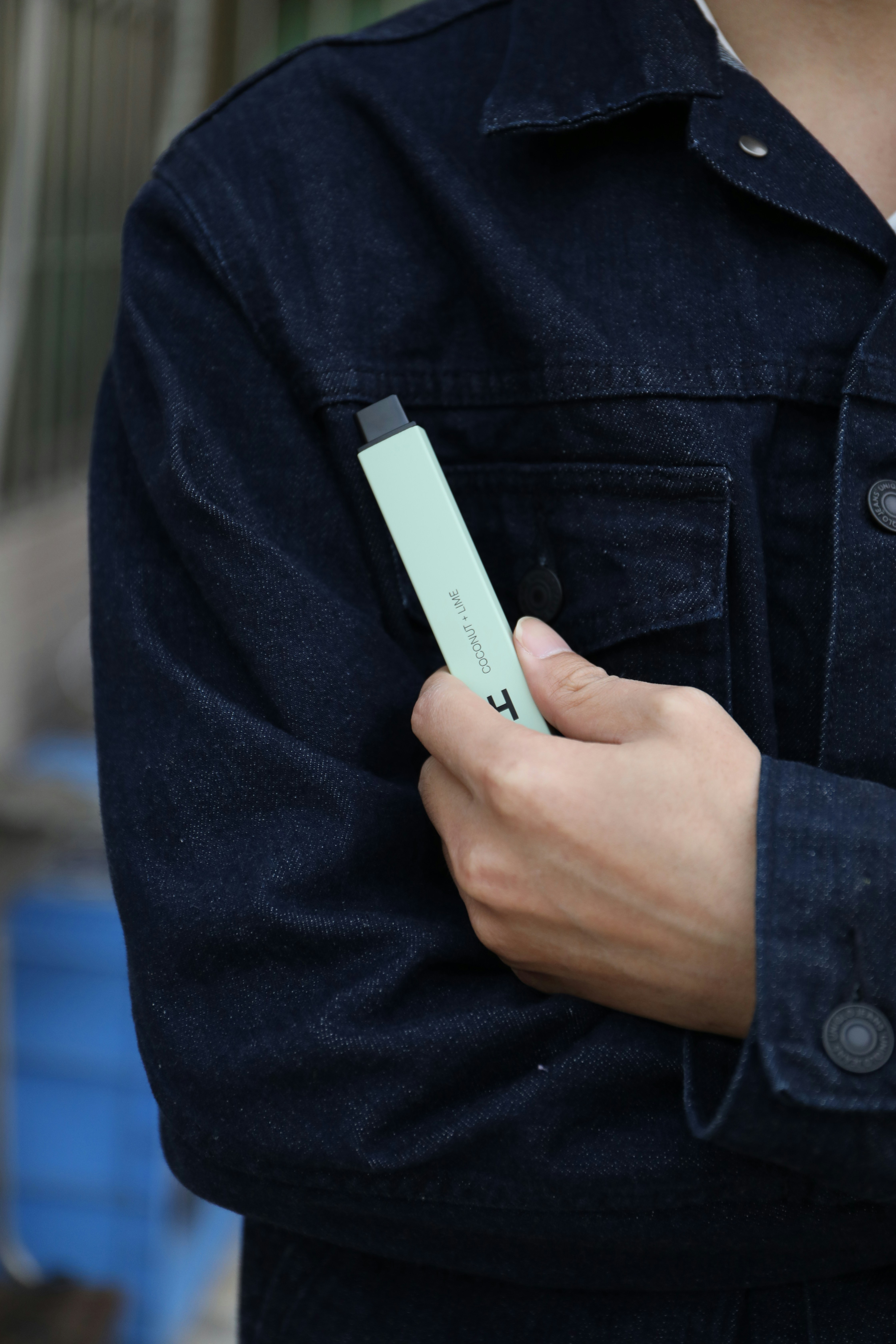 A mint green HYLA Peppermint nicotine-free guarana and l-dopa vape is held in the hand of a man wearing a denim shirt.