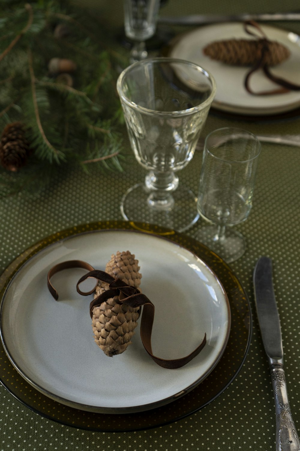 a place setting with a pine cone on a plate