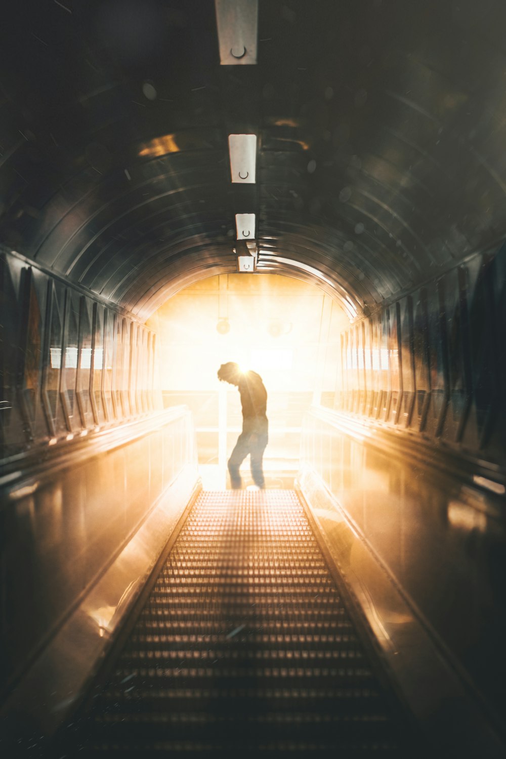 a man is walking down an escalator in a tunnel