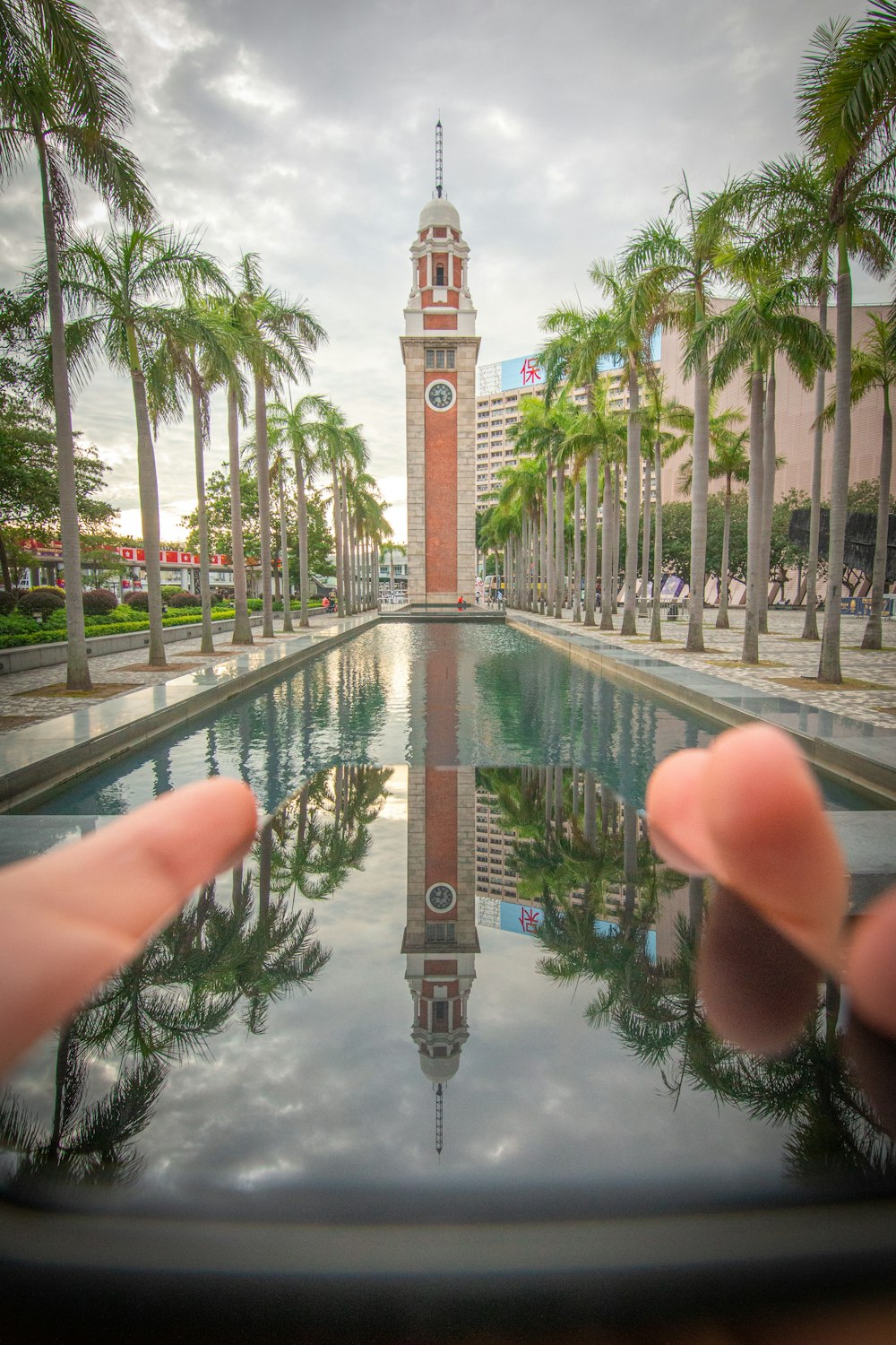 a person holding up a cell phone with a clock tower in the background