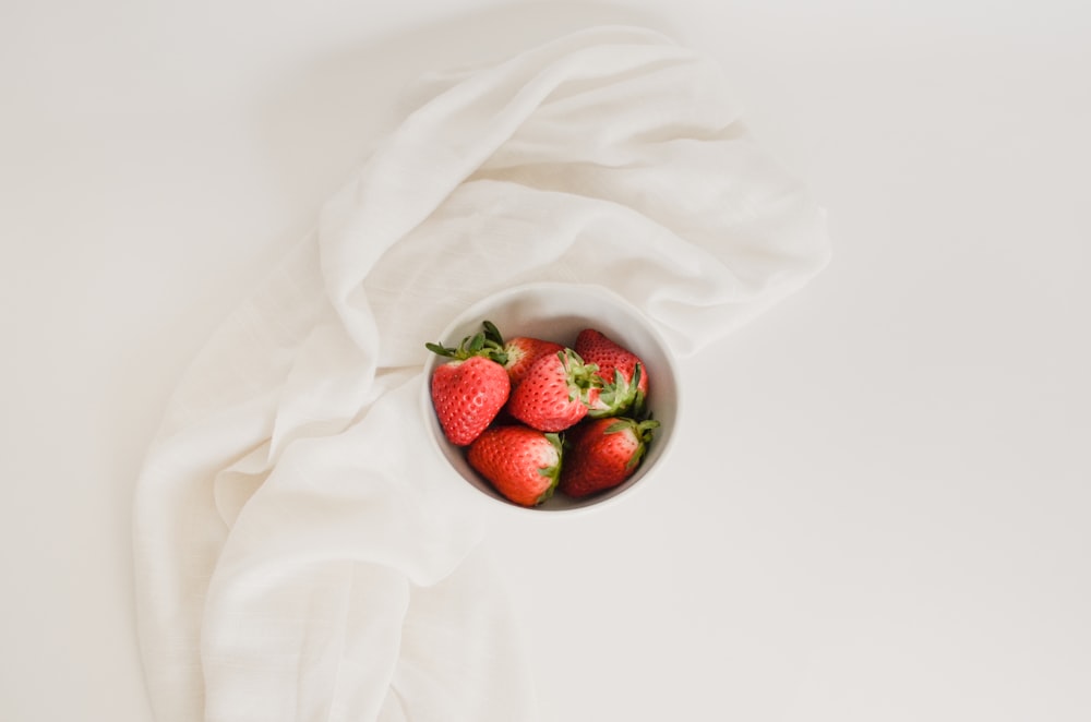 a bowl of strawberries on a white cloth