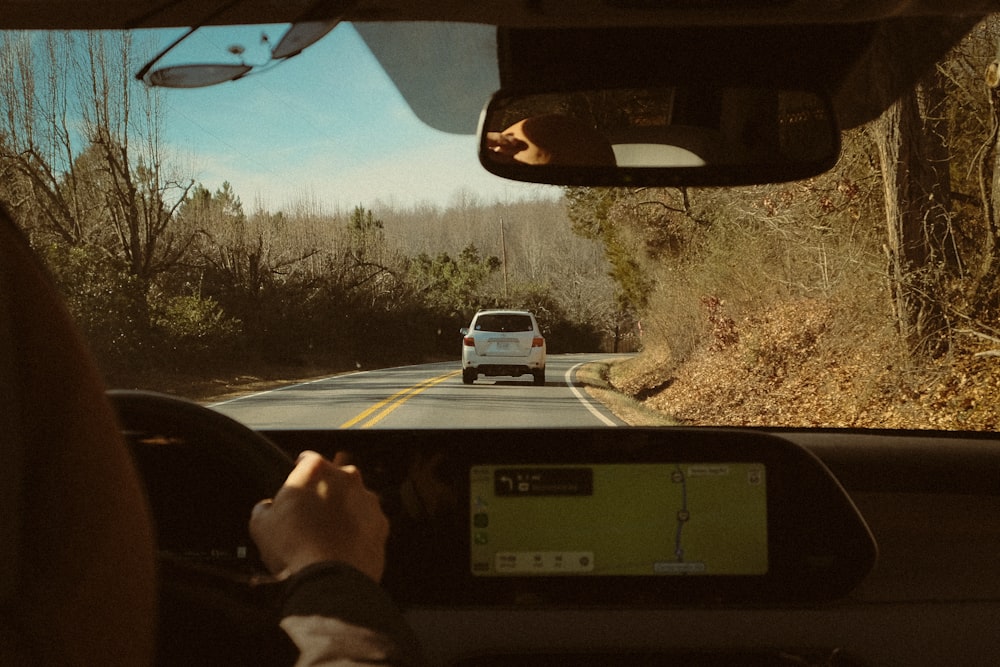 a person driving a car on a road next to a forest