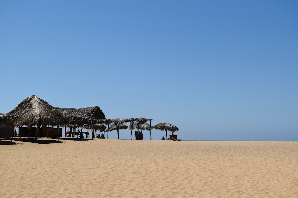 a group of straw umbrellas sitting on top of a sandy beach