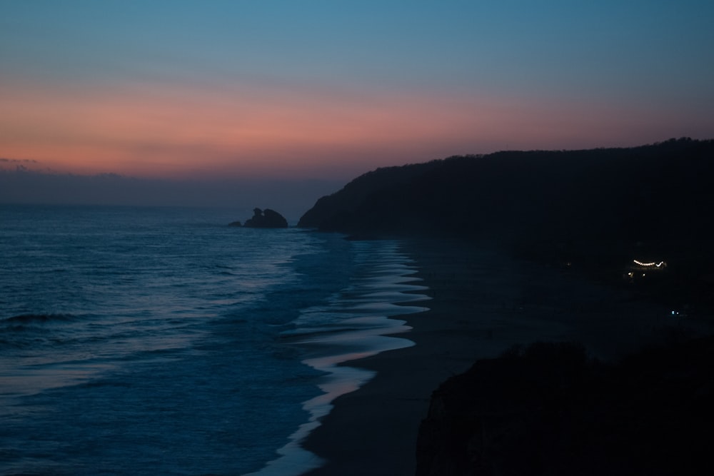 a sunset view of a beach with waves coming in