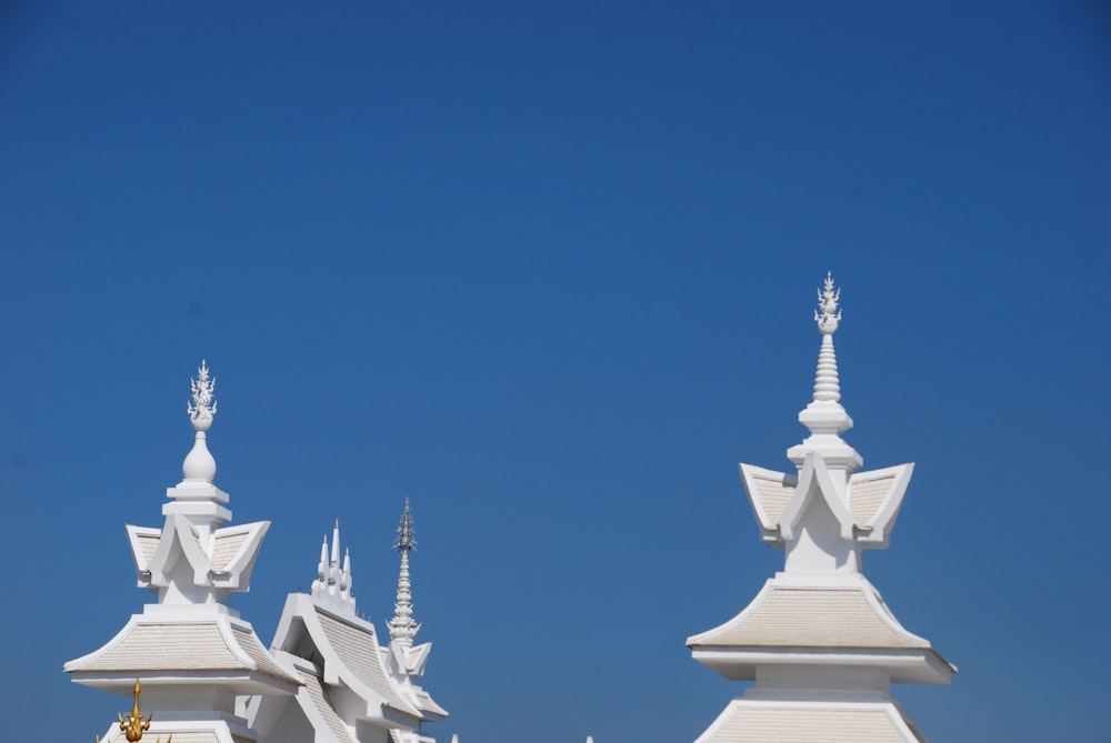 a row of white buildings with spires against a blue sky