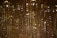 A close-up view of a shimmering crystal chandelier with numerous faceted prisms reflecting light and creating a warm, golden glow. The intricate detail of the crystals creates a luxurious and opulent effect.