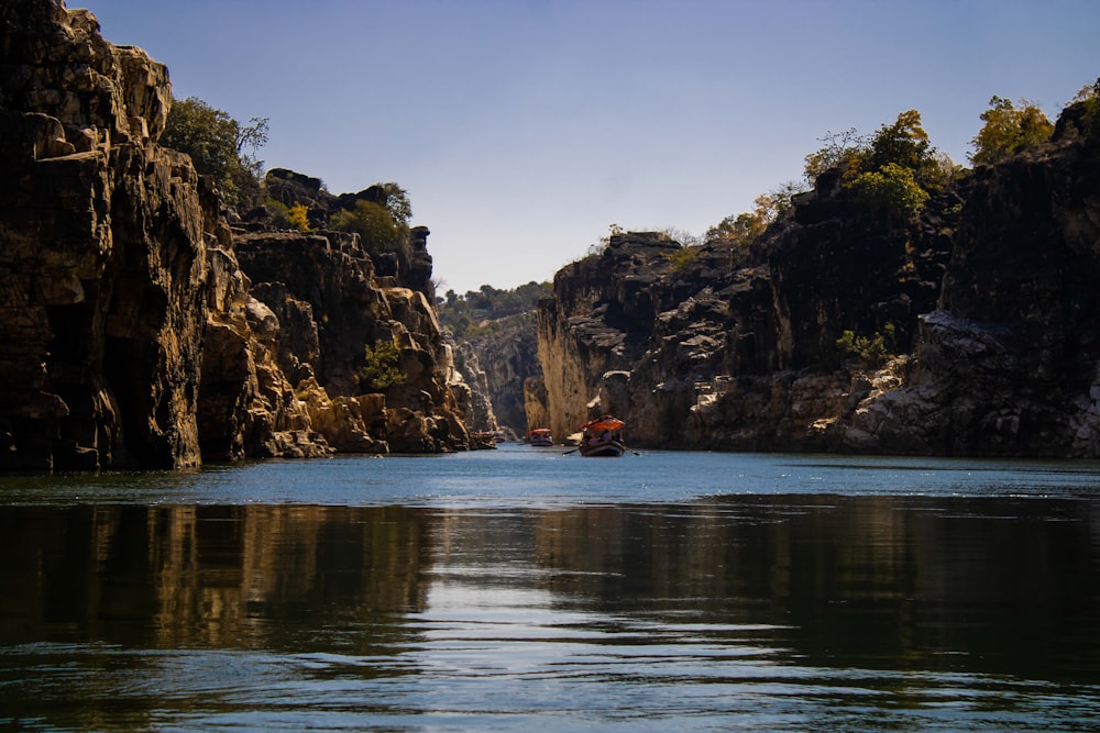 a boat traveling down a river surrounded by mountains